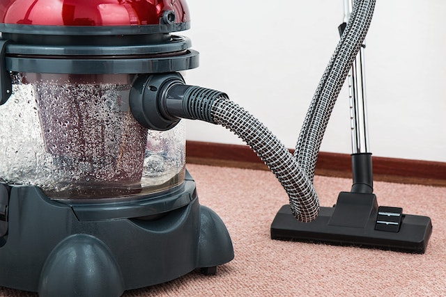 a black and red steamcleaner rests on a pink carpet